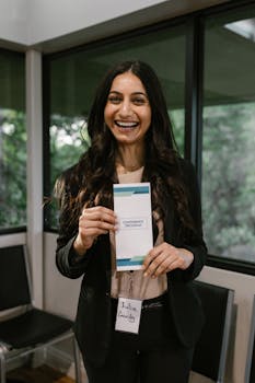 Professional woman smiling while holding a conference program in a modern office setting.