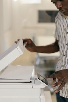 Close-up of a man operating a photocopier in an office setting, focusing on technology in workspaces.